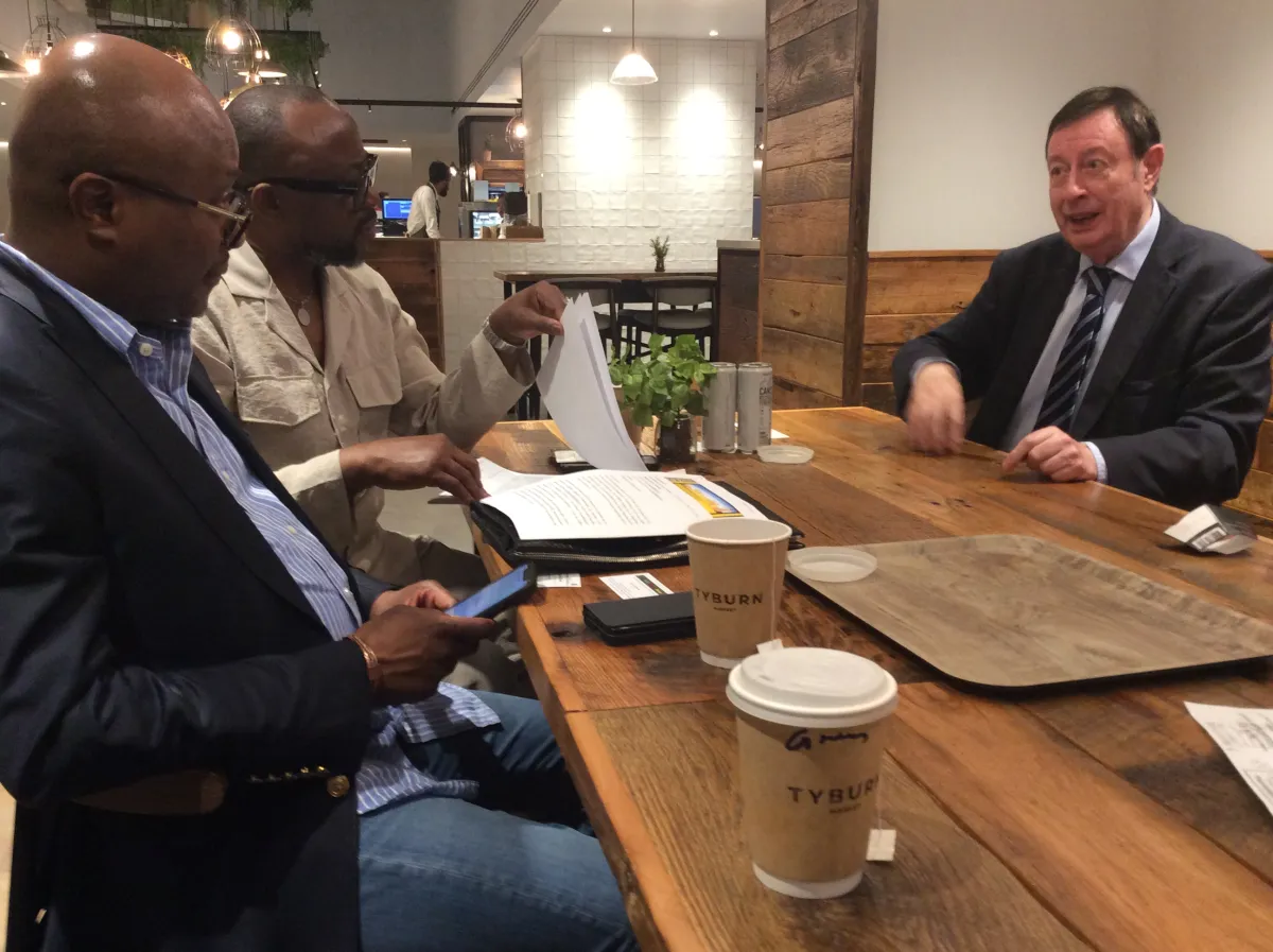 Three business leaders discussing documents over coffee at a table